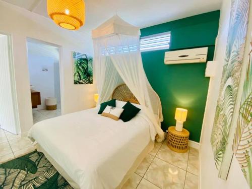 a bedroom with a white bed and a green wall at Les Orchidées de Sainte-Anne in Sainte-Anne