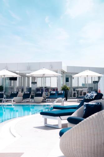 a swimming pool with lounge chairs and umbrellas at Millennium Downtown in Abu Dhabi