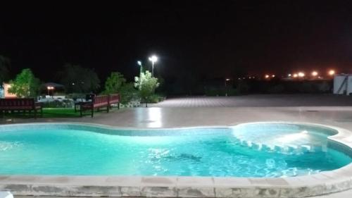 a swimming pool in the middle of a yard at night at Thefarm rak in Al Ḩamrānīyah