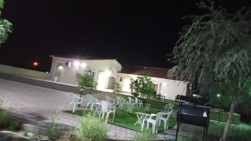 a group of white chairs in front of a house at night at Thefarm rak in Al Ḩamrānīyah