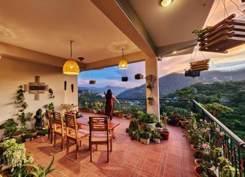 a woman standing on a balcony looking out the window at Rashmi Cottage - 4 BHK Villa with Serene Valley Views in Dagshai