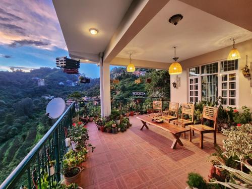 a balcony with a table and chairs and a view at Rashmi Cottage - 4 BHK Villa with Serene Valley Views in Dagshai