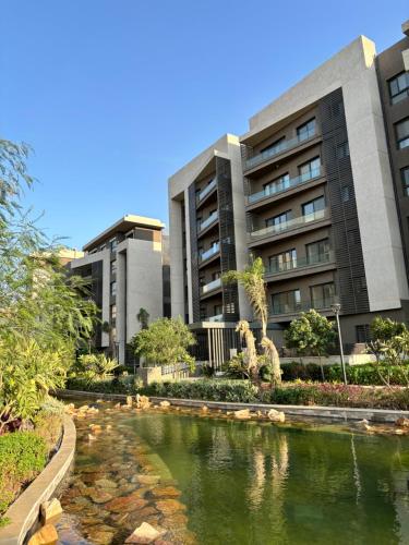a hotel with a pond in front of a building at 2BR Modern & Comfy Apartment in luxury neighbourhood in Madinaty