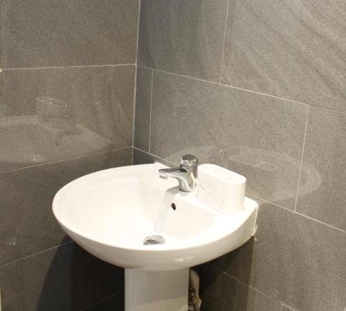 a bathroom with a white sink and a tub at Spacious 4-Bed House - Sleeps 5 Garden & Parking in London