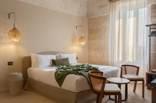 a bedroom with a bed and a table and chairs at Masseria Donna Menga - The Leading Hotels of the World in Torre Lapillo