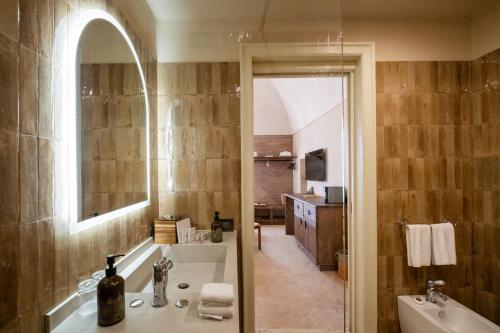 a bathroom with a tub and a sink and a mirror at Masseria Donna Menga - The Leading Hotels of the World in Torre Lapillo