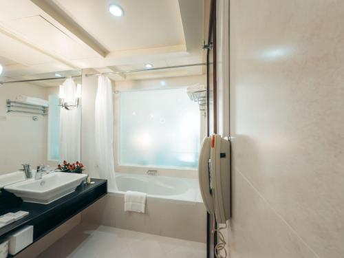 a bathroom with a tub and a sink and a bath tub at Kingsgate Hotel by Millennium in Abu Dhabi