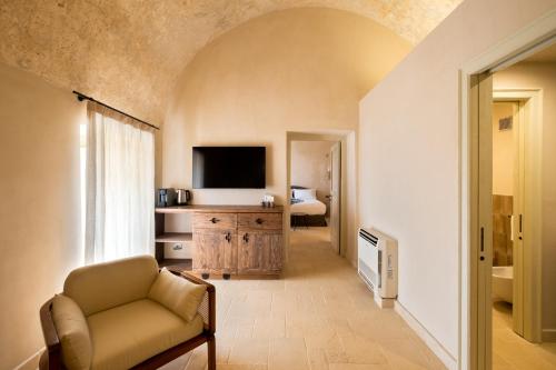 a living room with a couch and a television at Masseria Donna Menga - The Leading Hotels of the World in Torre Lapillo