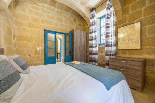 a bedroom with a bed and a stone wall at Room 8 - Couples room x 2 by Solea in Għarb