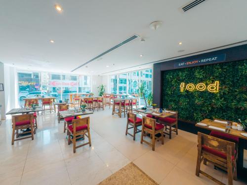 a restaurant with tables and chairs and a large green wall at Kingsgate Hotel by Millennium in Abu Dhabi