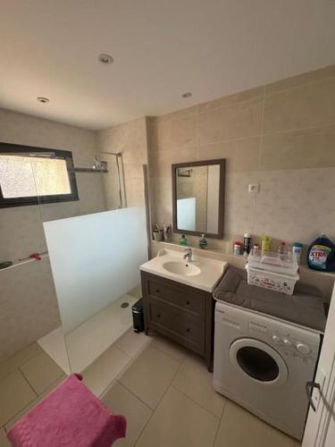 une salle de bain avec une machine à laver et un lavabo dans l'établissement Maison 3 chambres avec piscine, à Andernos-les-Bains
