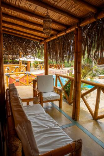 a porch with a bed and a chair under a pavilion at El Mirador de Vichayito in Vichayito