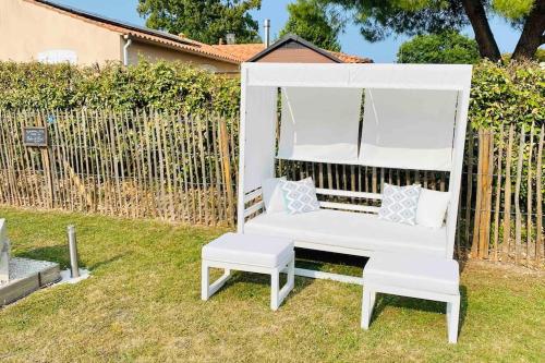 a white chair and a bench in a yard at Le Grenier - Gîte de Charme La Rochelle in Saint-Médard-dʼAunis