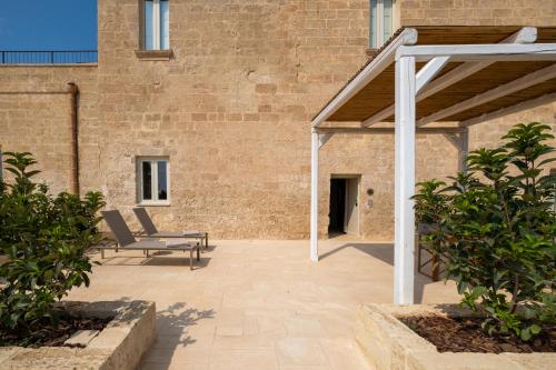 a patio with two lounge chairs in front of a brick building at Masseria Donna Menga - The Leading Hotels of the World in Torre Lapillo