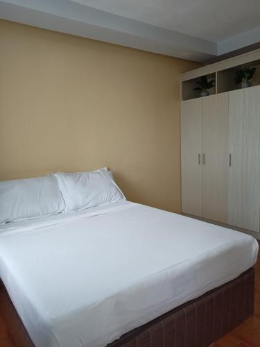 a bedroom with a large white bed and a cabinet at REI Condotel Seawind Davao in Davao City