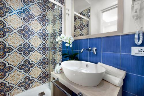 a bathroom with a white sink and blue tiles at Camalù Sorrento in Sorrento