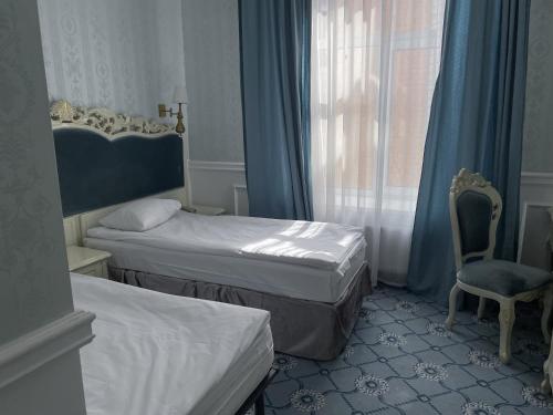 a room with two beds and a chair and a window at Royal Grand Hotel in Kyiv