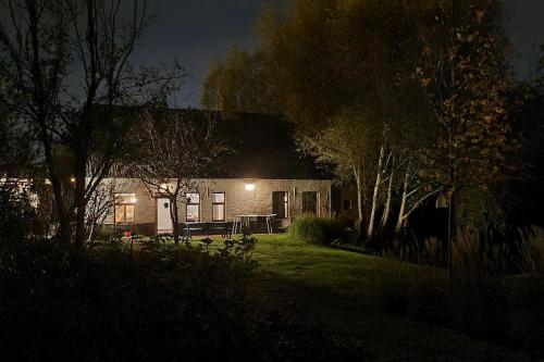 a house with a light on the side of it at night at City Farmhouse and studio in Roeselare