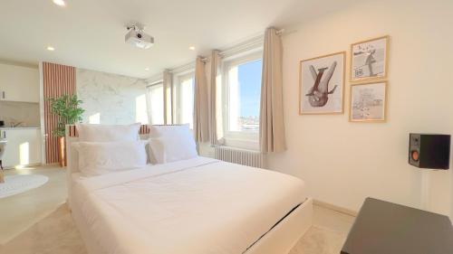 un lit blanc dans une chambre avec une fenêtre dans l'établissement PS5, Cinéma & Jacuzzi - Skyline Luxe, à Saint-Étienne