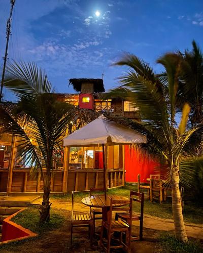 a table and chairs in front of a building with palm trees at El Mirador de Vichayito in Vichayito