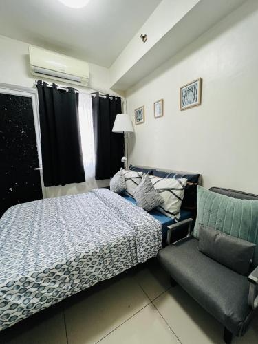 a bedroom with a bed and a couch and a window at Sea Breeze Studio Manila in Manila