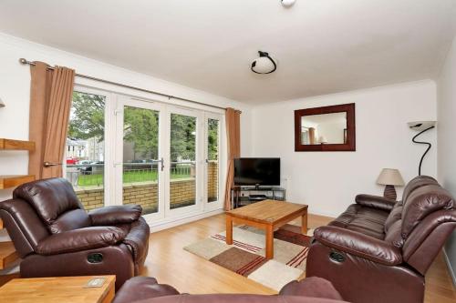 a living room with two leather chairs and a television at Spacious 4 bedroom Townhouse near Scenic Beach & City Centre in Aberdeen