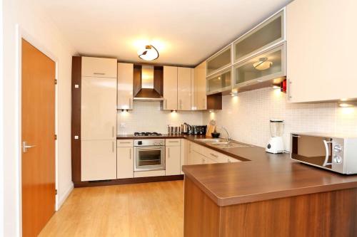 a kitchen with white cabinets and a wooden counter top at Spacious 4 bedroom Townhouse near Scenic Beach & City Centre in Aberdeen