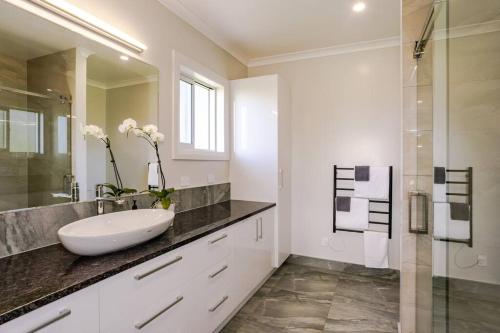 a white bathroom with a sink and a mirror at Fraters Escape - Martinborough in Martinborough 