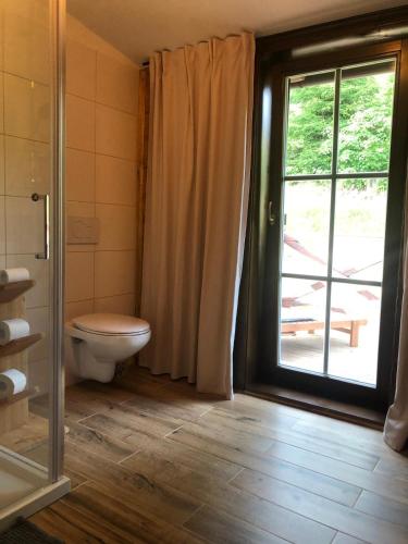 a bathroom with a toilet and a large window at Chalupa Grúnik in Zázrivá