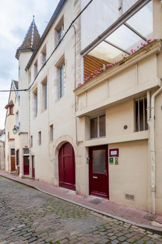 a building with red doors on a cobblestone street at Residence Beaune Sweet Home, 4 Appartements d'exception avec parking inclus in Beaune