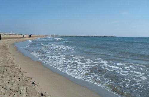 a beach with the ocean and people walking on it at L'étape méditerranéenne logement 4-6 personnes avec parking privé in Sauvian