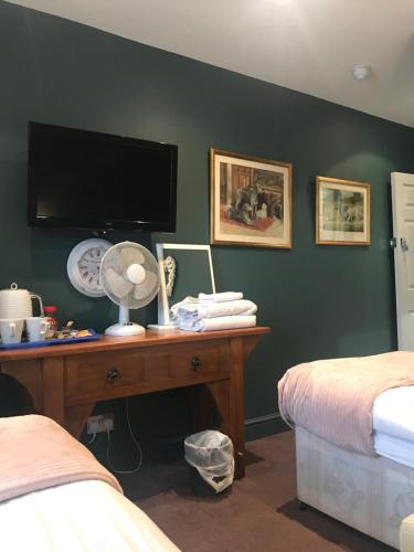 a bedroom with a desk with a flat screen tv at Acacia Villas Guest House in Guildford