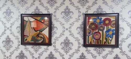two framed paintings on a wall with a wallpaper at Keviz Homestay in Jawāharnagar
