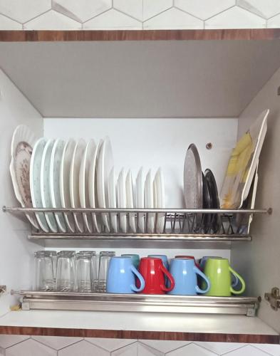 a shelf with plates and mugs in a kitchen at Keviz Homestay in Jawāharnagar