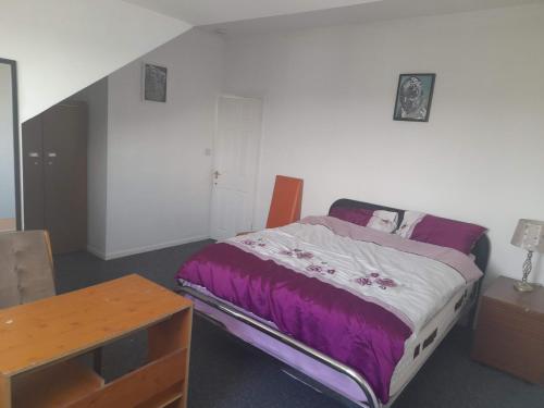 a bedroom with a bed with purple sheets and a table at ACCANE in Sunderland