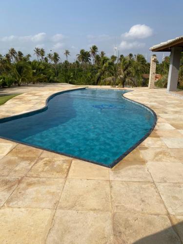a swimming pool with blue water on a patio at Mansão Guajiru Suítes in Guajiru