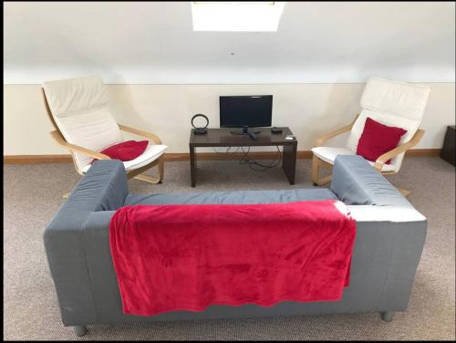 a living room with two chairs and a couch with a red blanket at Detached loft, stunning city views in Drumbo