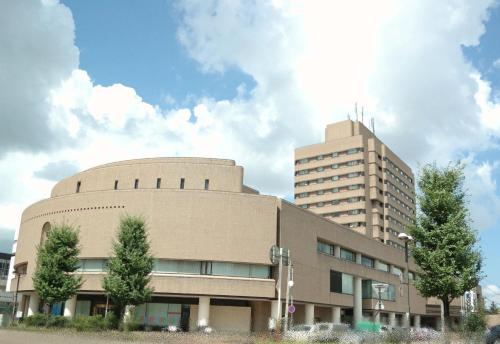 a large building with a tall building in the background at Hotel New Otani Nagaoka in Nagaoka