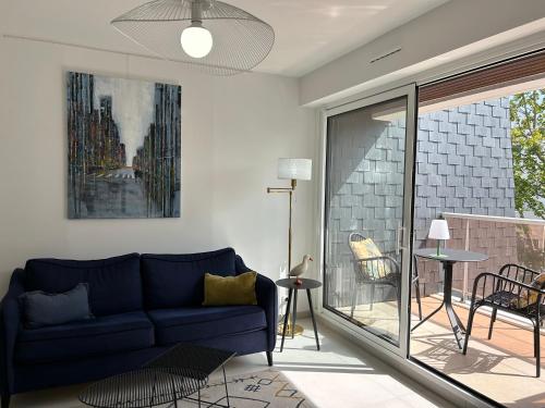 un salon avec un canapé bleu et un balcon dans l'établissement Corniche - Bénodet, à Bénodet