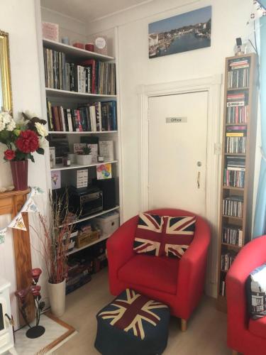 a living room with a red chair and a book shelf at Beachcomber Guesthouse in Weymouth