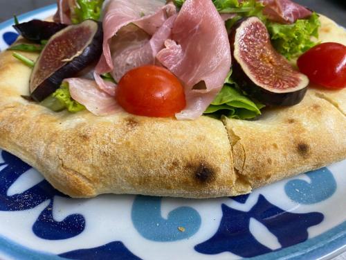 a plate with a sandwich with salad and tomatoes on it at Fachwerk-Hotel Eisenbart in Hannoversch Münden