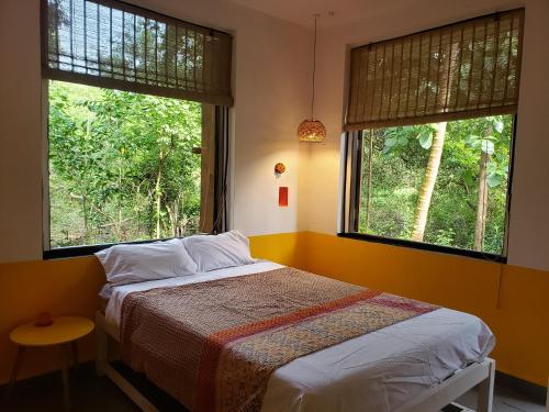 a bedroom with a bed and two windows with trees at Laxmi Happy Home in Querim Goa in Querim
