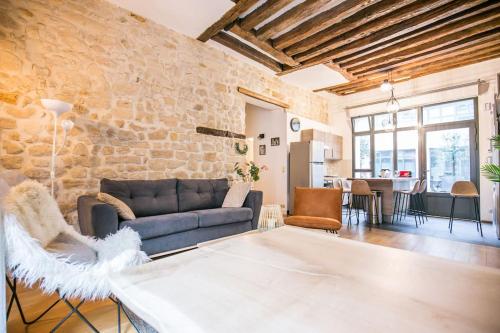un salon avec un canapé et un mur en pierre dans l'établissement Cœur de Voltaire - Loft cosy Parisien, à Paris
