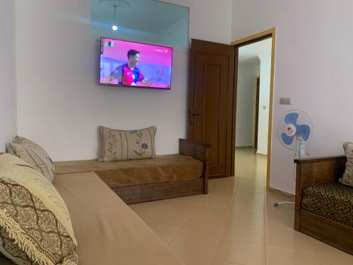 a living room with a couch and a tv on the wall at شقة مفروشة in Beni Enzar