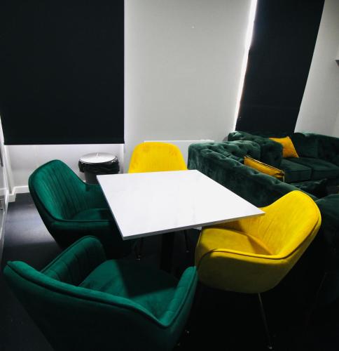a room with a white table and green chairs at NE1 City Studios & Apartments in Newcastle upon Tyne