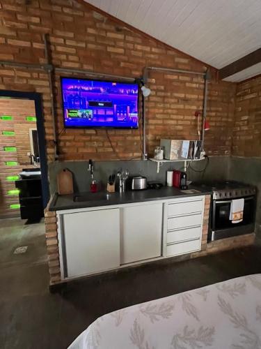 a kitchen with a sink and a tv on a brick wall at Refugio do Amor in São João del Rei