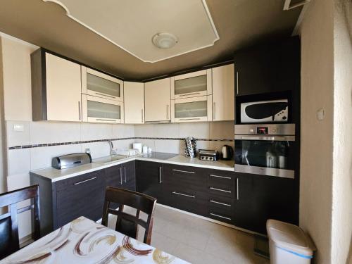 a kitchen with black and white cabinets and a table at Apartman Veki in Subotica
