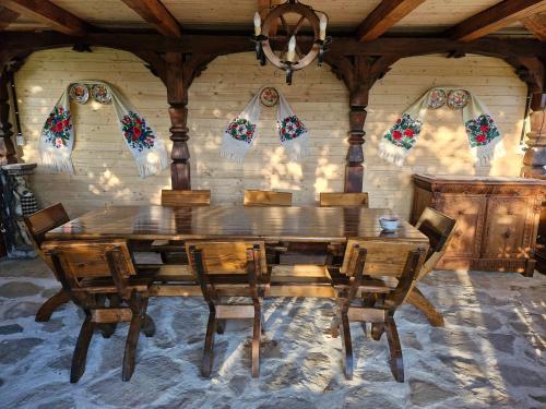 a dining room with a wooden table and chairs at Emma's Lake Houses in Bîrsana