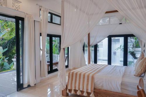 a bedroom with a bed with curtains and windows at J4 Villa Ubud in Ubud