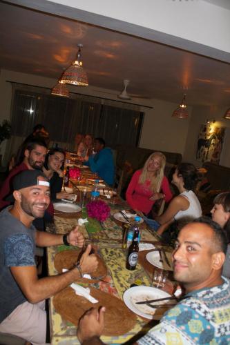 a group of people sitting around a long table at Happy Days Guest House in Le Morne